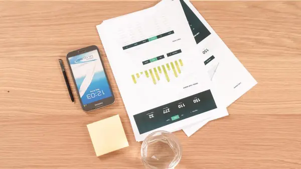 Informes impresos con gráficos junto a un celular sobre un escritorio