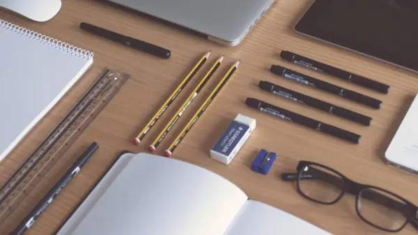 Escritorio ordenado con notebook, cuadernos y lápices para iniciar un negocio